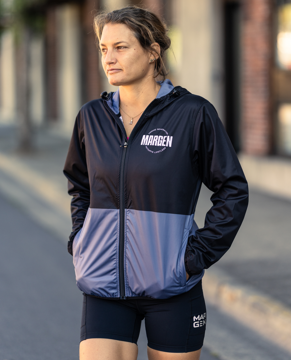 Woman wearing the DRIFT Women's Jacket by MARGEN, walking outdoors in an urban setting.